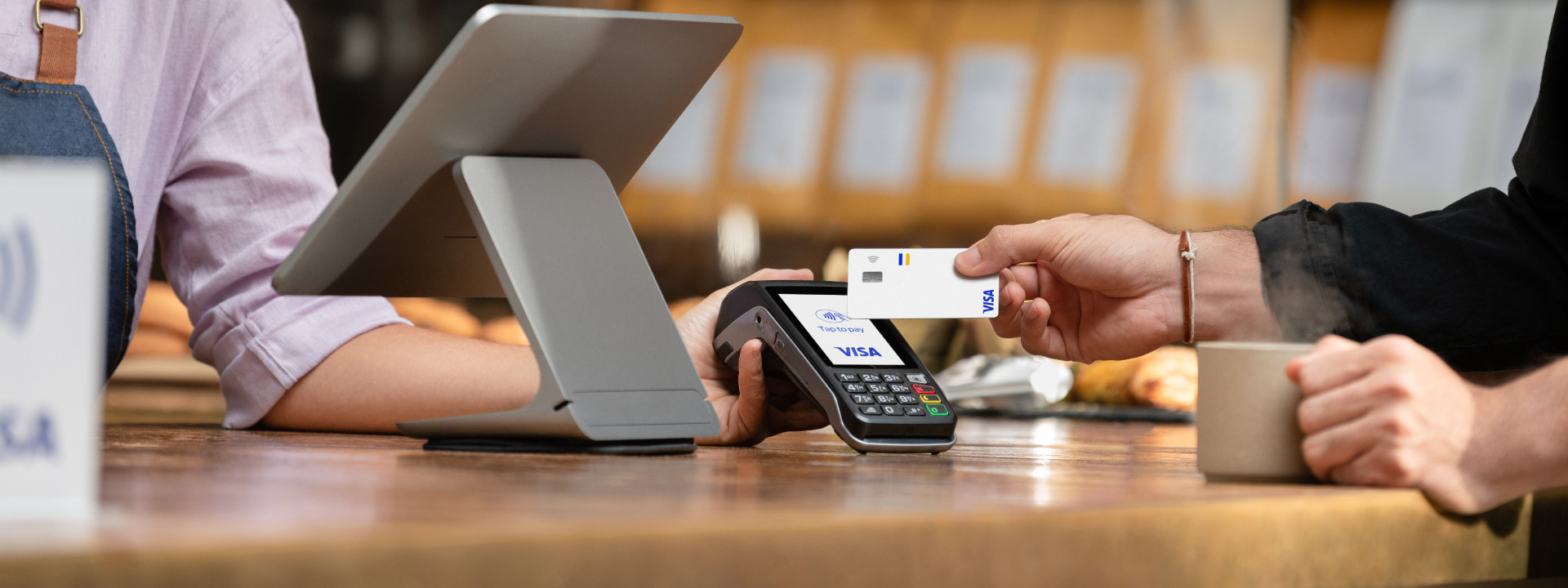 someone tapping their card on a card reader to pay at a till