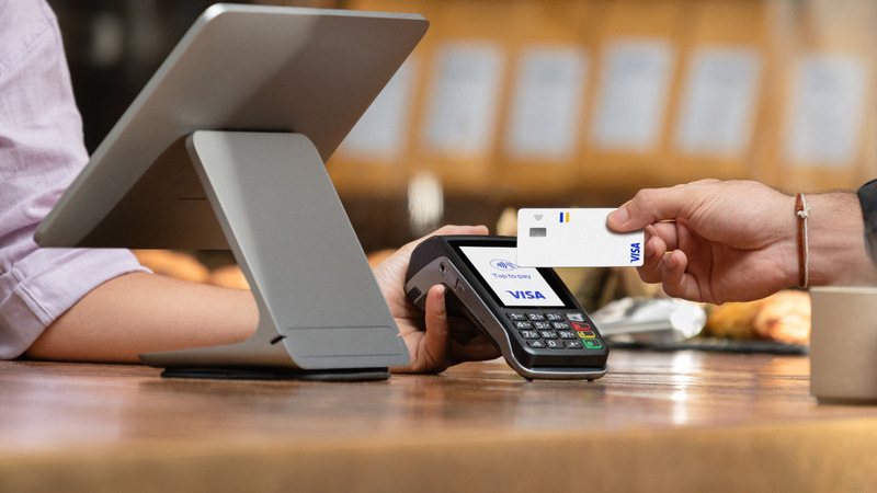 someone tapping their card on a card reader to pay at a till